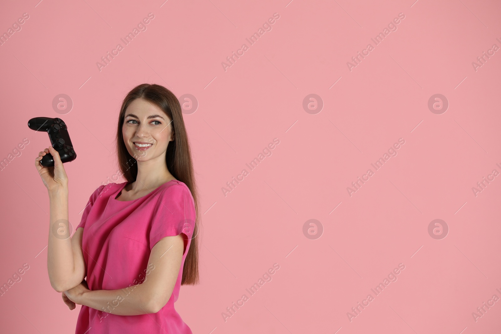 Photo of Happy woman with controller on pink background, space for text