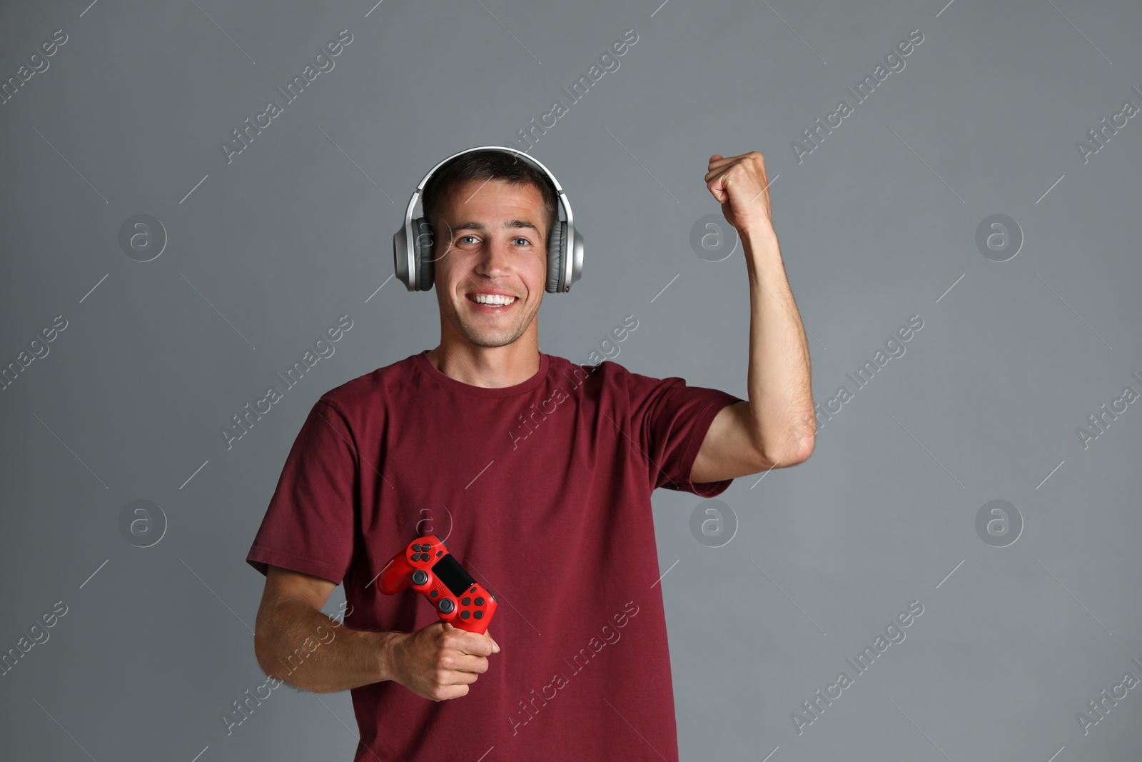 Photo of Happy man in headphones with controller on gray background