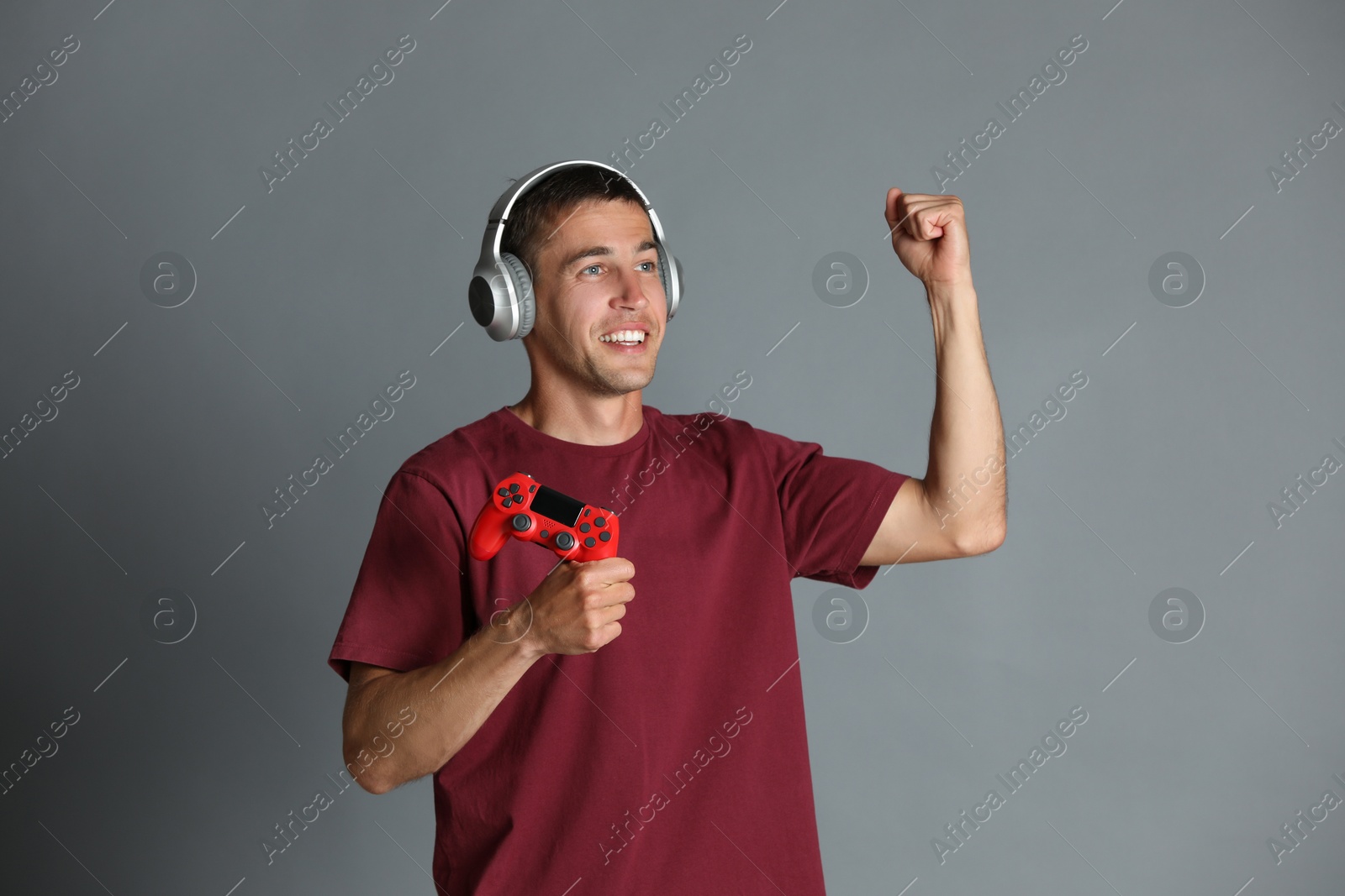 Photo of Happy man in headphones with controller on gray background