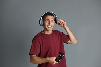 Photo of Surprised man in headphones with controller on gray background