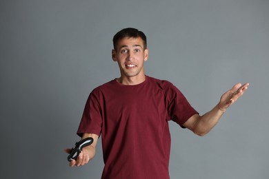 Surprised man with controller on gray background