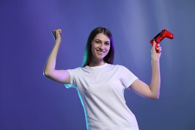 Photo of Happy woman with controller on violet background