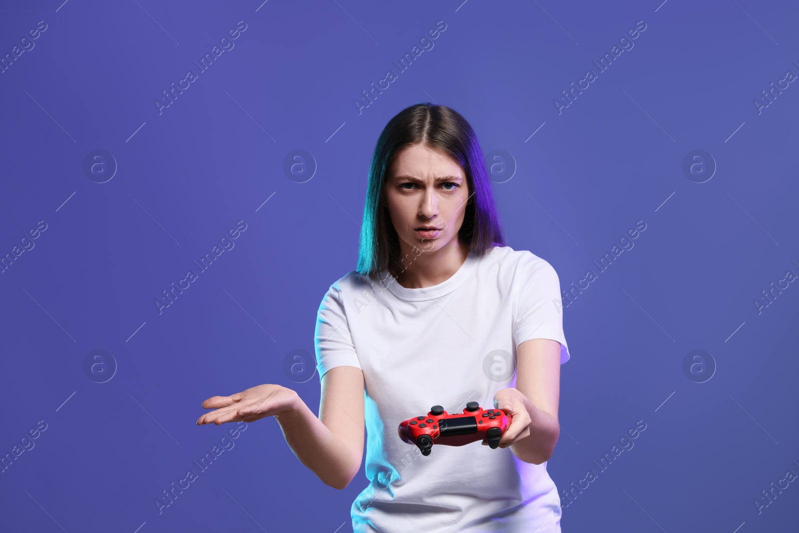 Photo of Surprised woman playing video games with controller on violet background