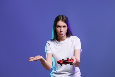 Photo of Surprised woman playing video games with controller on violet background