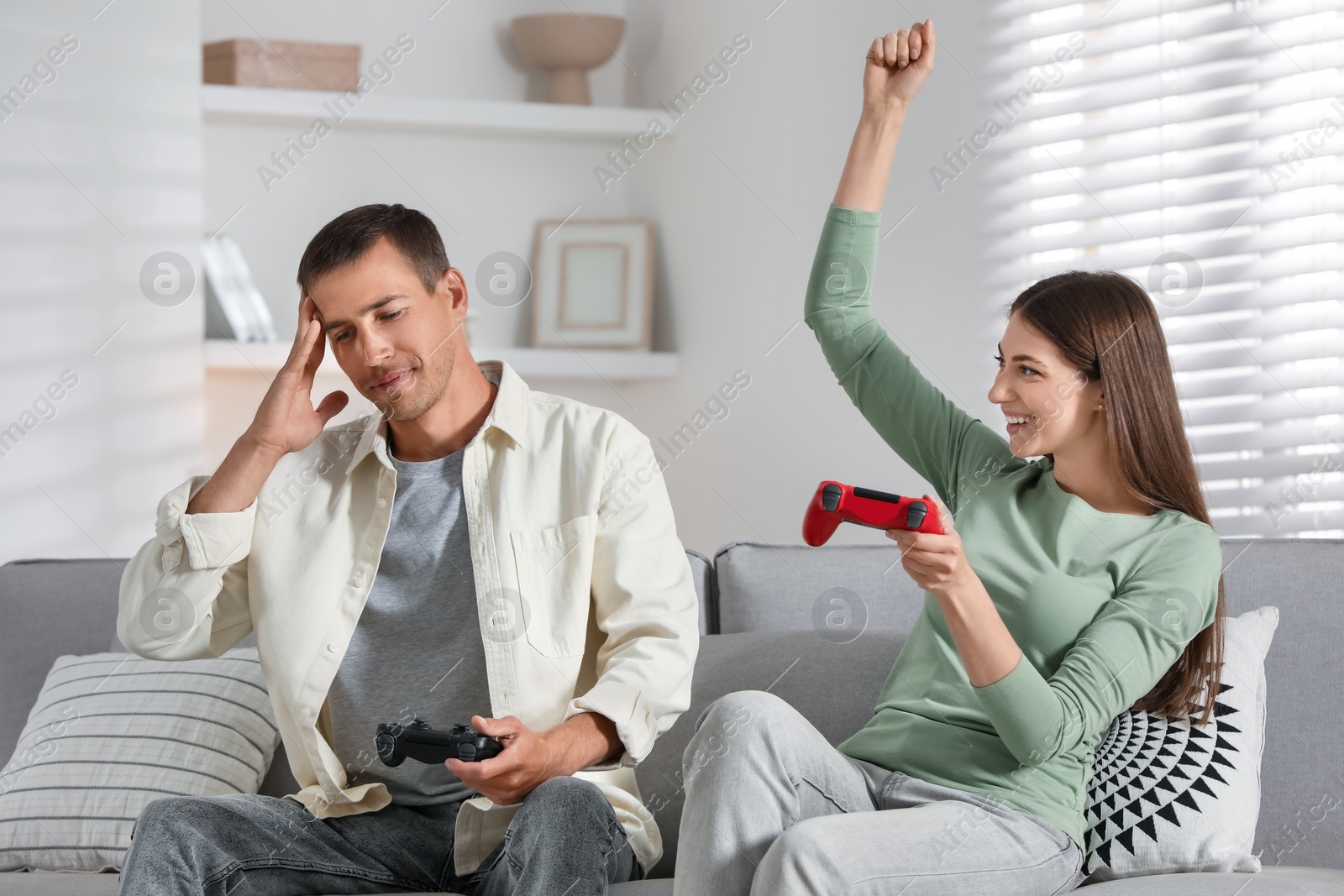 Photo of Couple playing video games with controllers at home