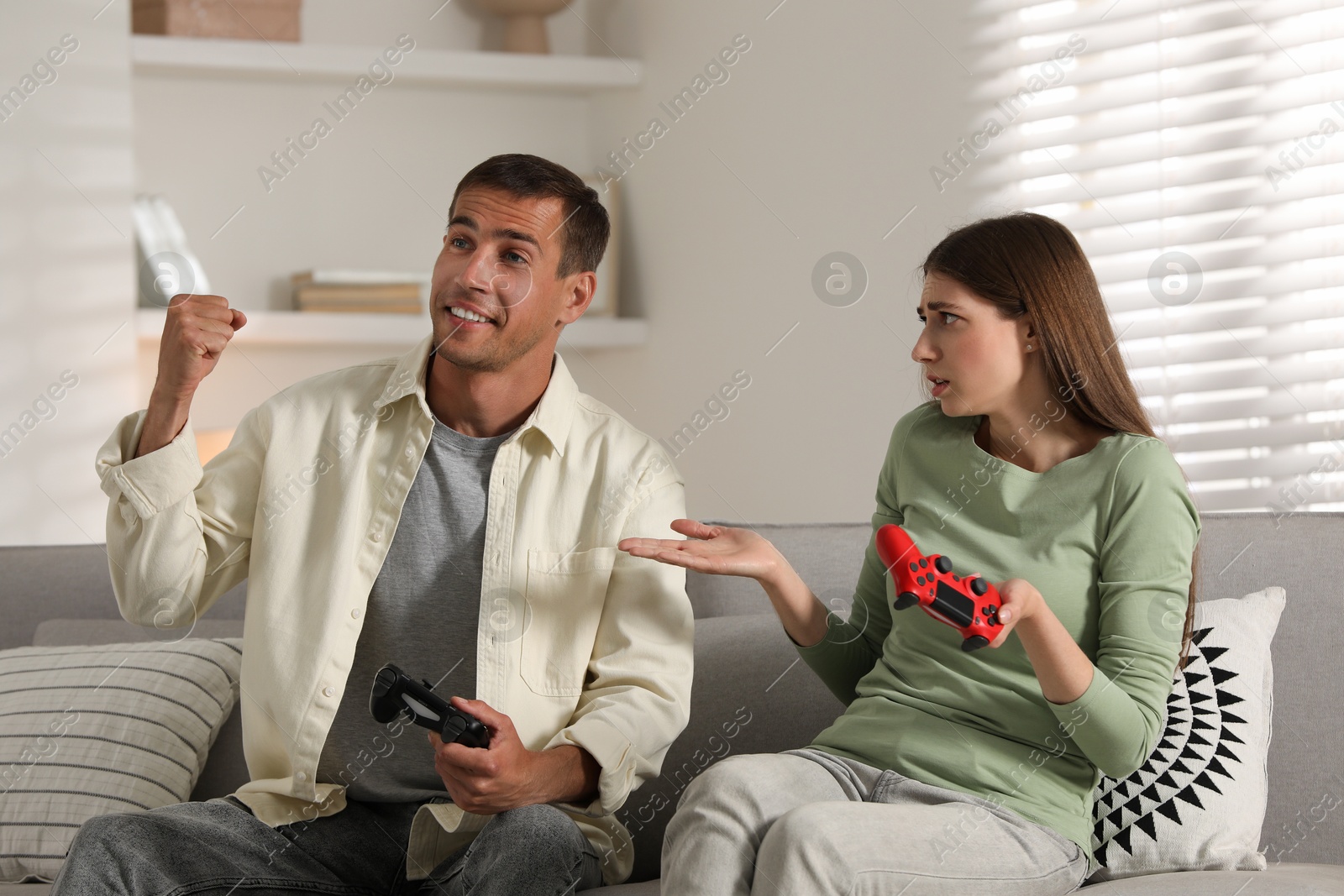 Photo of Couple playing video games with controllers at home