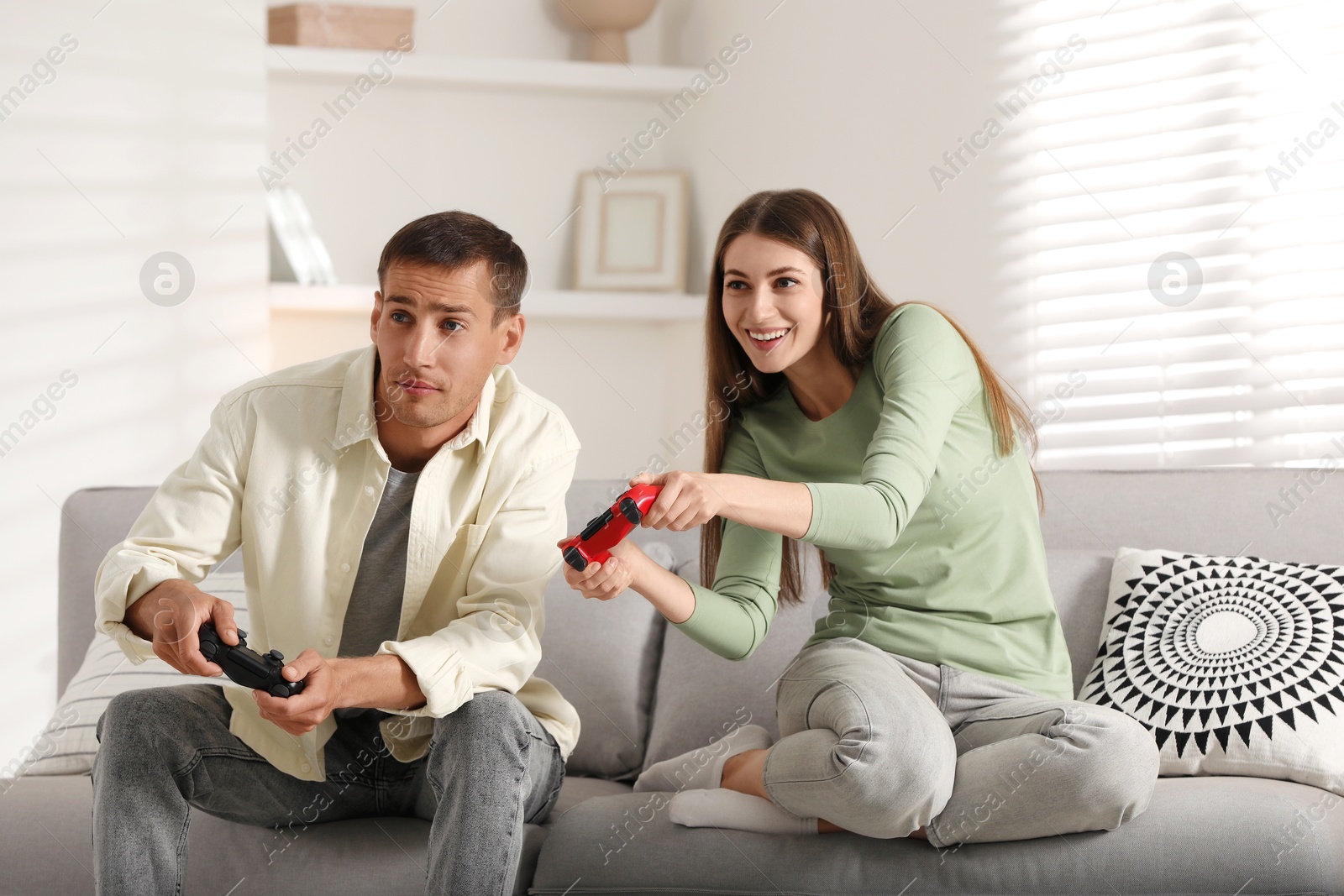 Photo of Couple playing video games with controllers at home