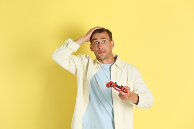 Unhappy man with controller on yellow background