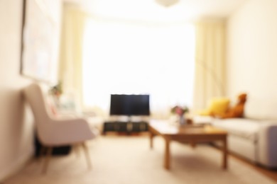 Photo of Blurred view of cozy living room with modern furniture and TV set. Interior design