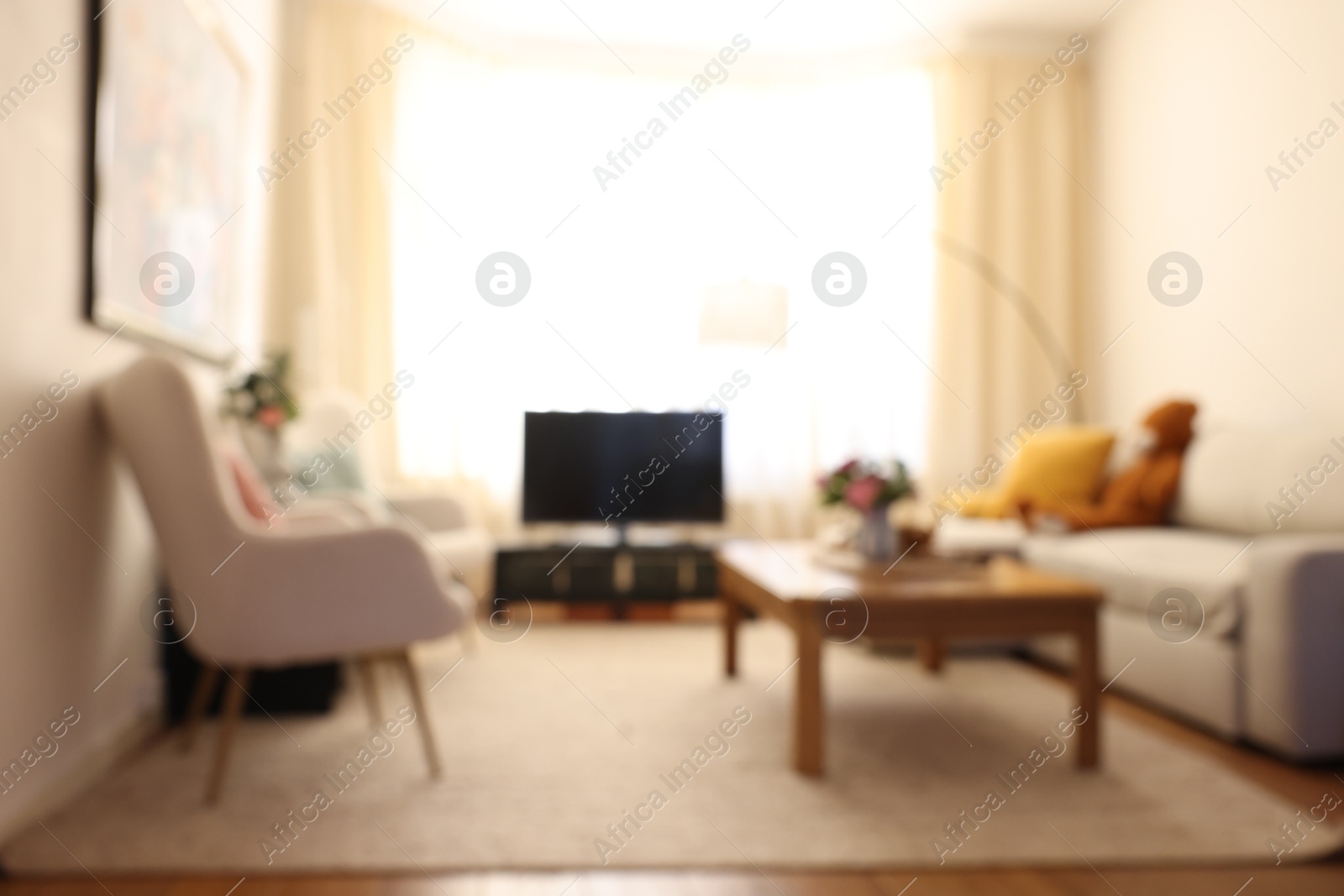 Photo of Blurred view of cozy living room with modern furniture and TV set. Interior design