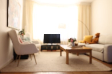 Photo of Blurred view of cozy living room with modern furniture and TV set. Interior design