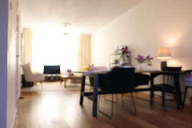 Photo of Stylish dining room interior with comfortable furniture and bouquet of flowers, blurred view