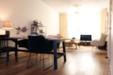 Photo of Stylish dining room interior with comfortable furniture and bouquet of flowers, blurred view