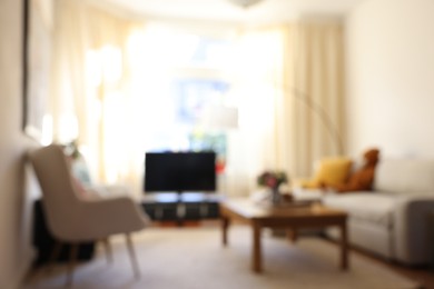 Photo of Blurred view of cozy living room with modern furniture and TV set. Interior design