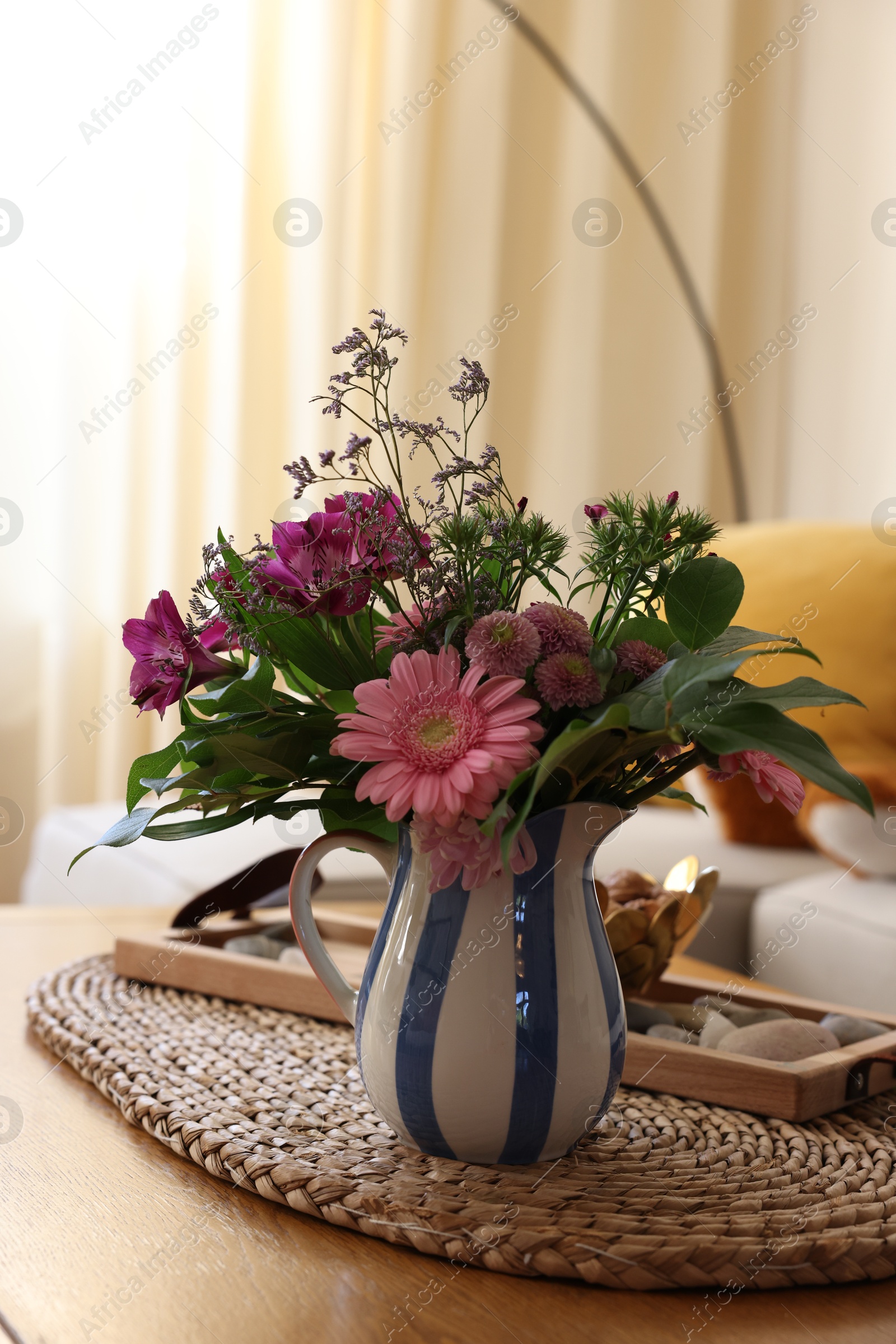 Photo of Bouquet of beautiful flowers in vase on wooden table at home