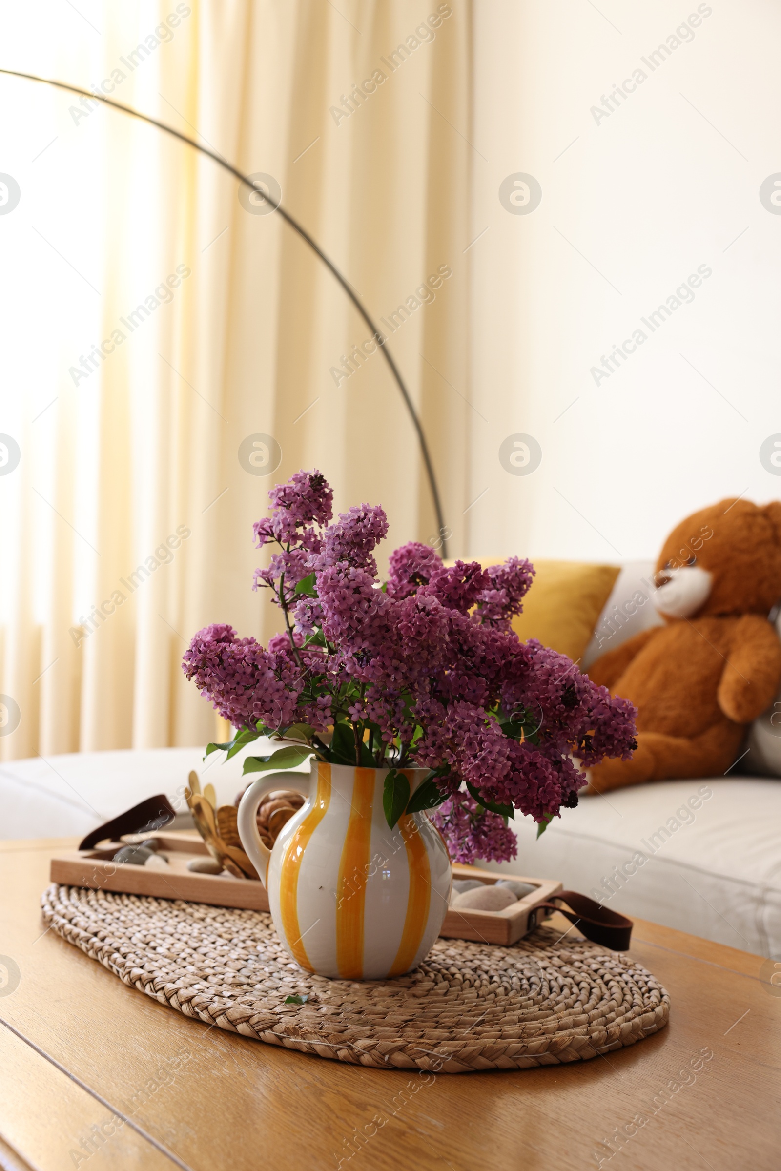 Photo of Beautiful fragrant lilac flowers in vase on table at home