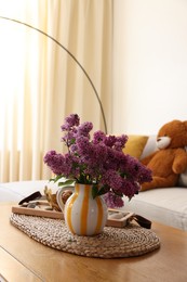 Photo of Beautiful fragrant lilac flowers in vase on table at home