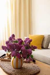 Photo of Beautiful fragrant lilac flowers in vase on table at home