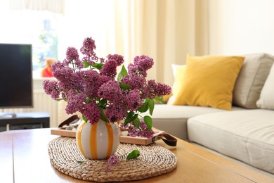 Photo of Beautiful fragrant lilac flowers in vase on table at home. Space for text