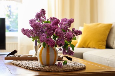 Photo of Beautiful fragrant lilac flowers in vase on table at home