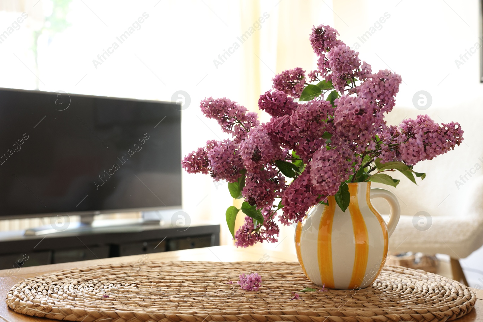 Photo of Beautiful lilac flowers in vase on table at home. Space for text