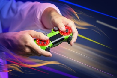 Man playing video game with controller on color background, closeup. Flames near device, motion blur effect