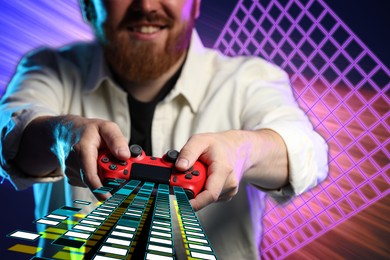 Image of Happy man playing video game with controller on bright background, closeup. Game elements coming out from device