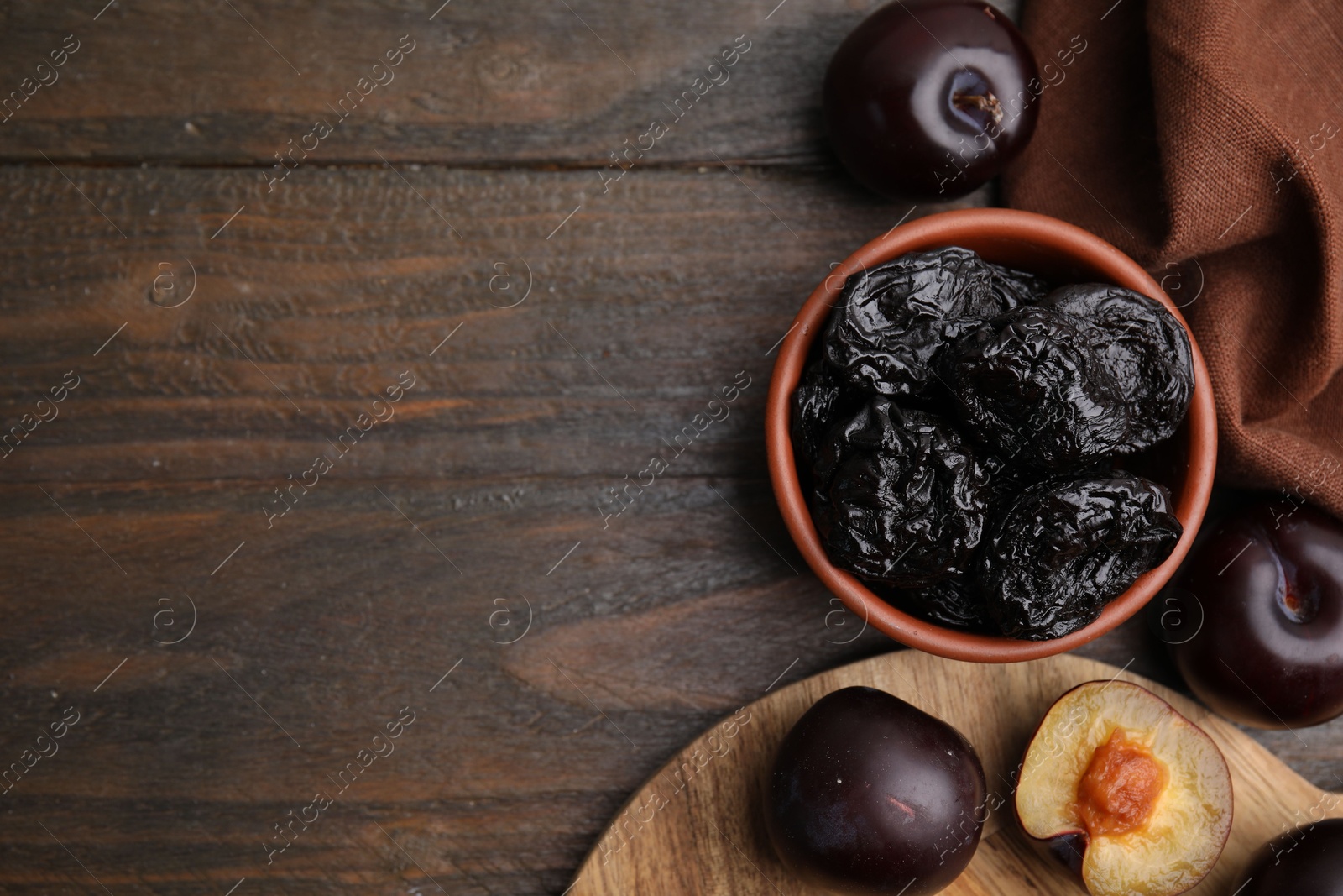 Photo of Delicious prunes in bowl and fresh ripe plums on wooden table, flat lay. Space for text