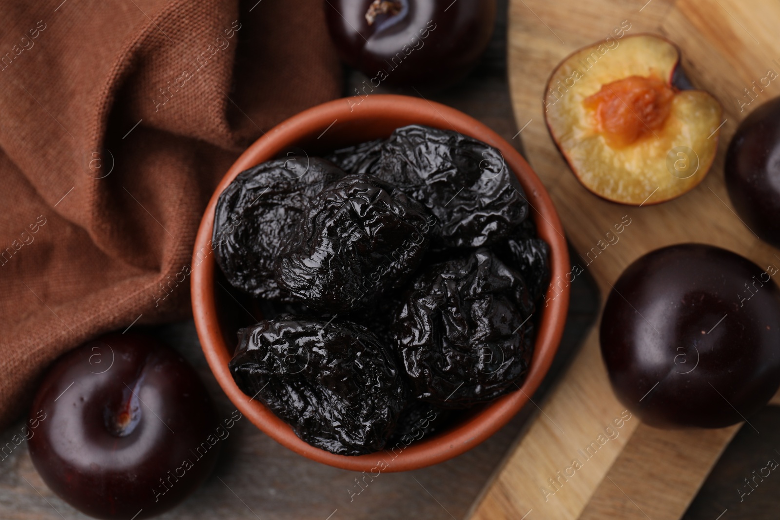 Photo of Delicious prunes in bowl and fresh ripe plums on wooden table, flat lay