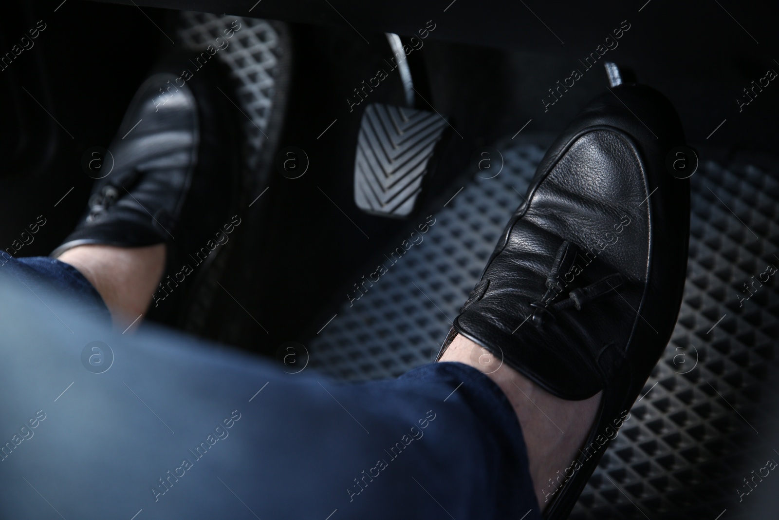 Photo of Man in black shoes pushing on pedal of car brake, closeup