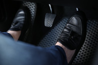 Photo of Man in black shoes pushing on pedal of car brake, closeup