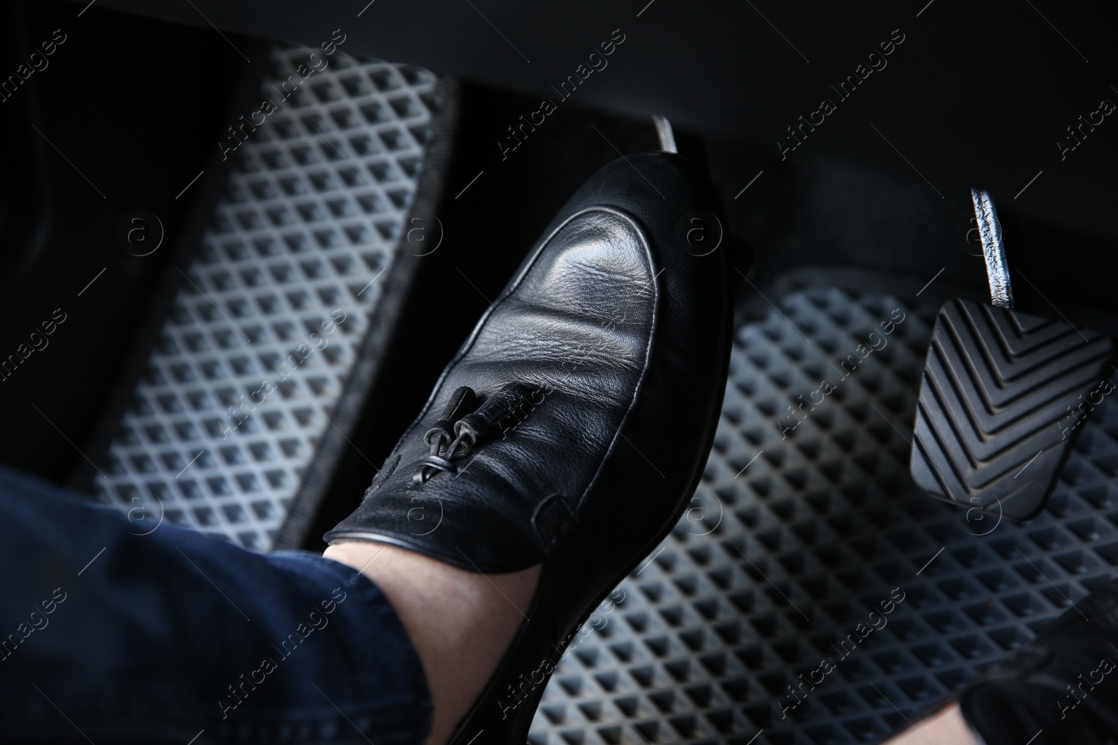 Photo of Man in black shoes pushing on pedal of car brake, closeup