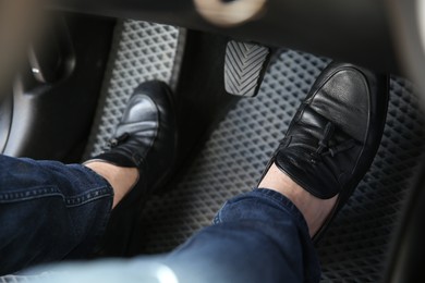 Photo of Man in black shoes pushing on pedal of car brake, closeup
