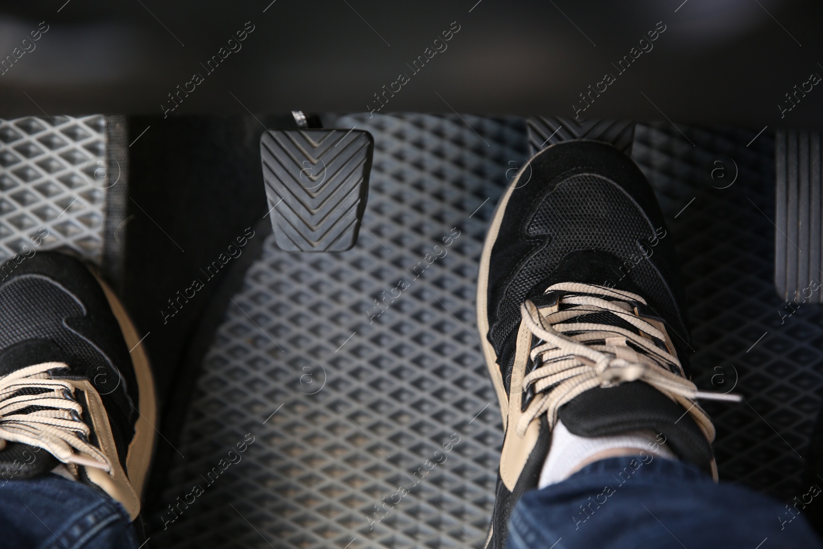 Photo of Man in sneakers pushing on pedal of car brake, closeup