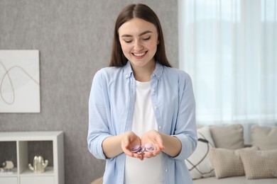 Photo of Expecting twins. Pregnant woman holding two pacifiers at home