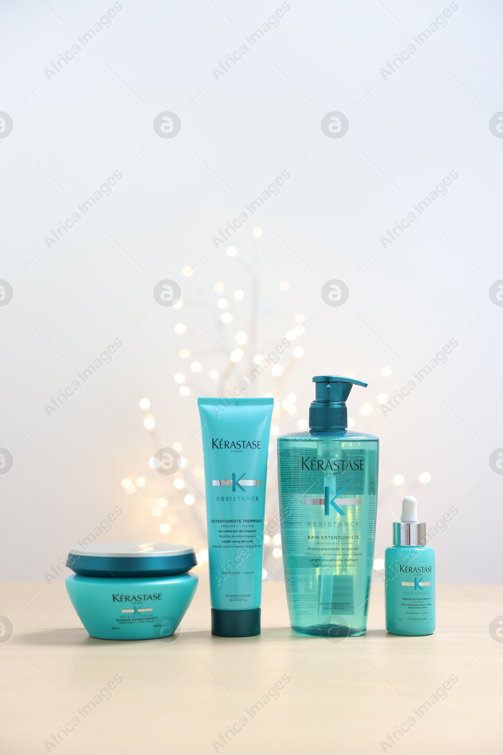 Photo of Leiden, Netherlands - June 11, 2024: Kerastase hair care cosmetic products on wooden table against light background with blurred lights, space for text