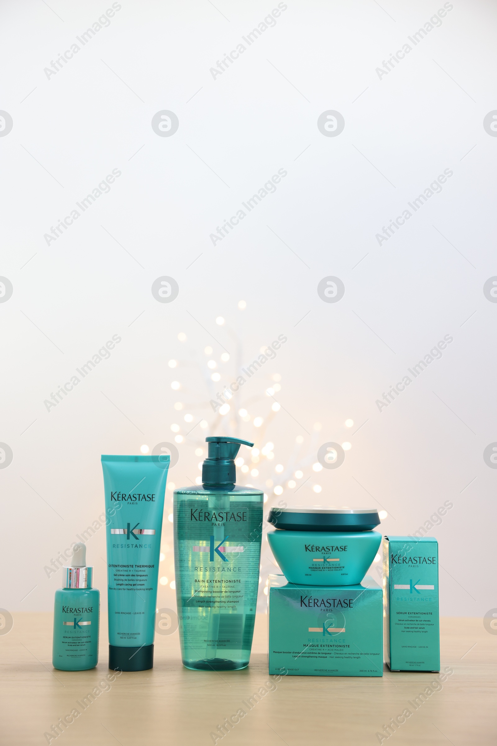 Photo of Leiden, Netherlands - June 11, 2024: Kerastase hair care cosmetic products on wooden table against light background with blurred lights, space for text