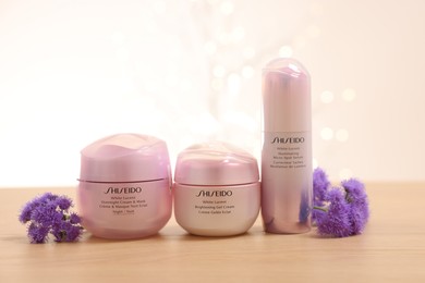 Photo of Leiden, Netherlands - June 11, 2024: Shiseido care cosmetic products and ageratum flowers on wooden table against light background