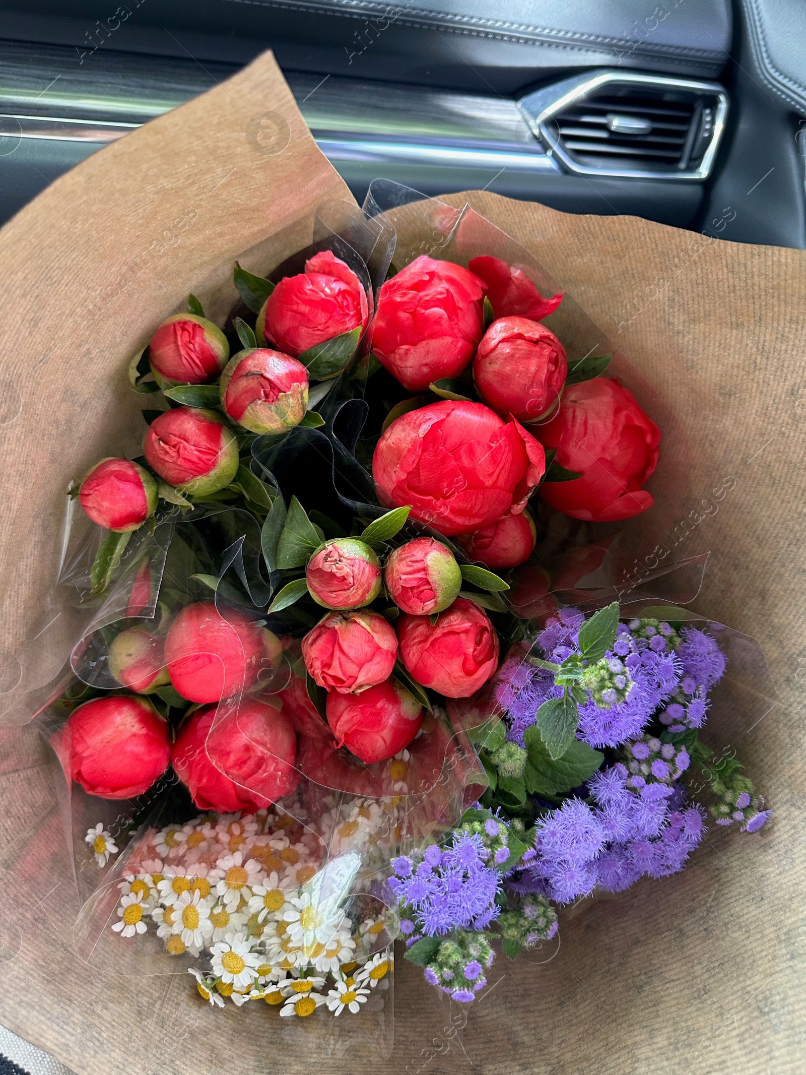 Photo of Bouquets of beautiful flowers in car, closeup