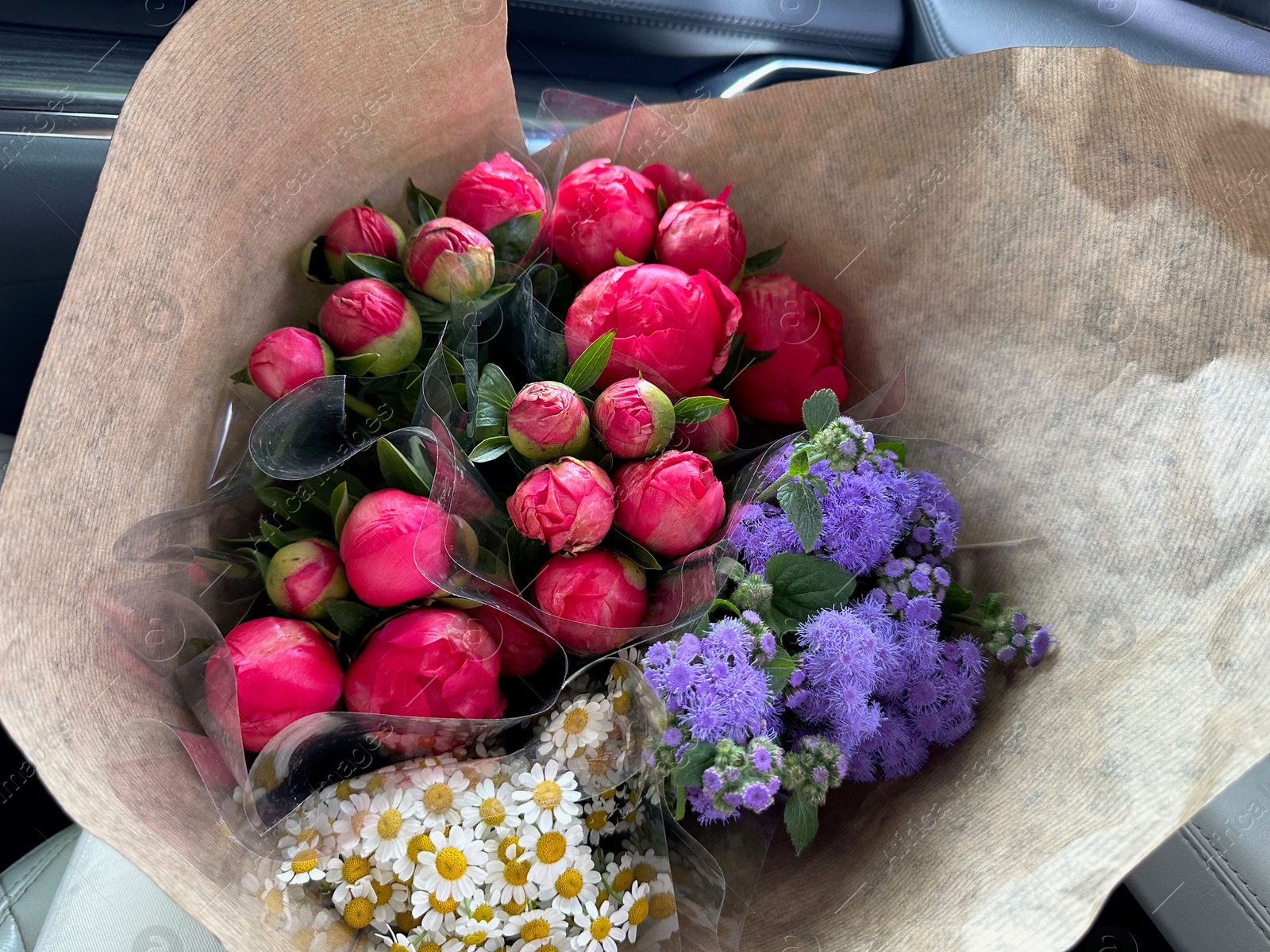 Photo of Bouquets of beautiful flowers in car, closeup