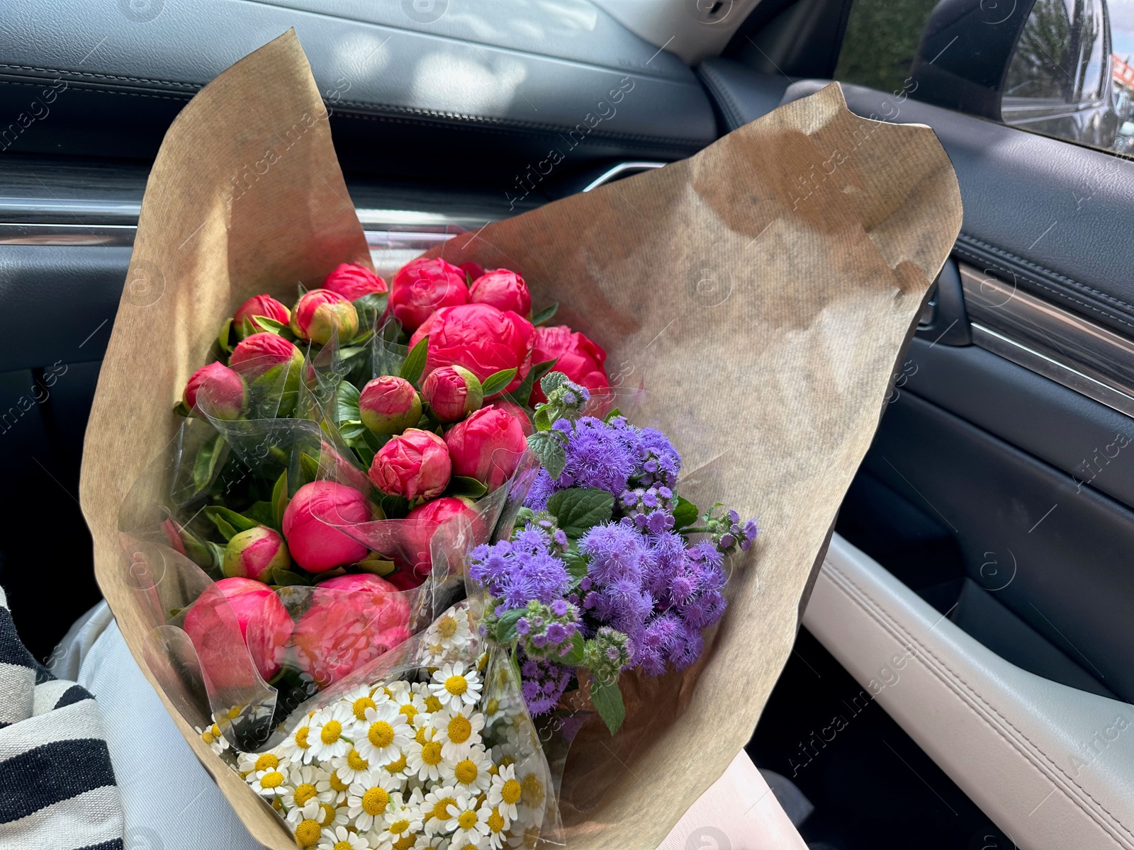 Photo of Bouquets of beautiful flowers in car, closeup