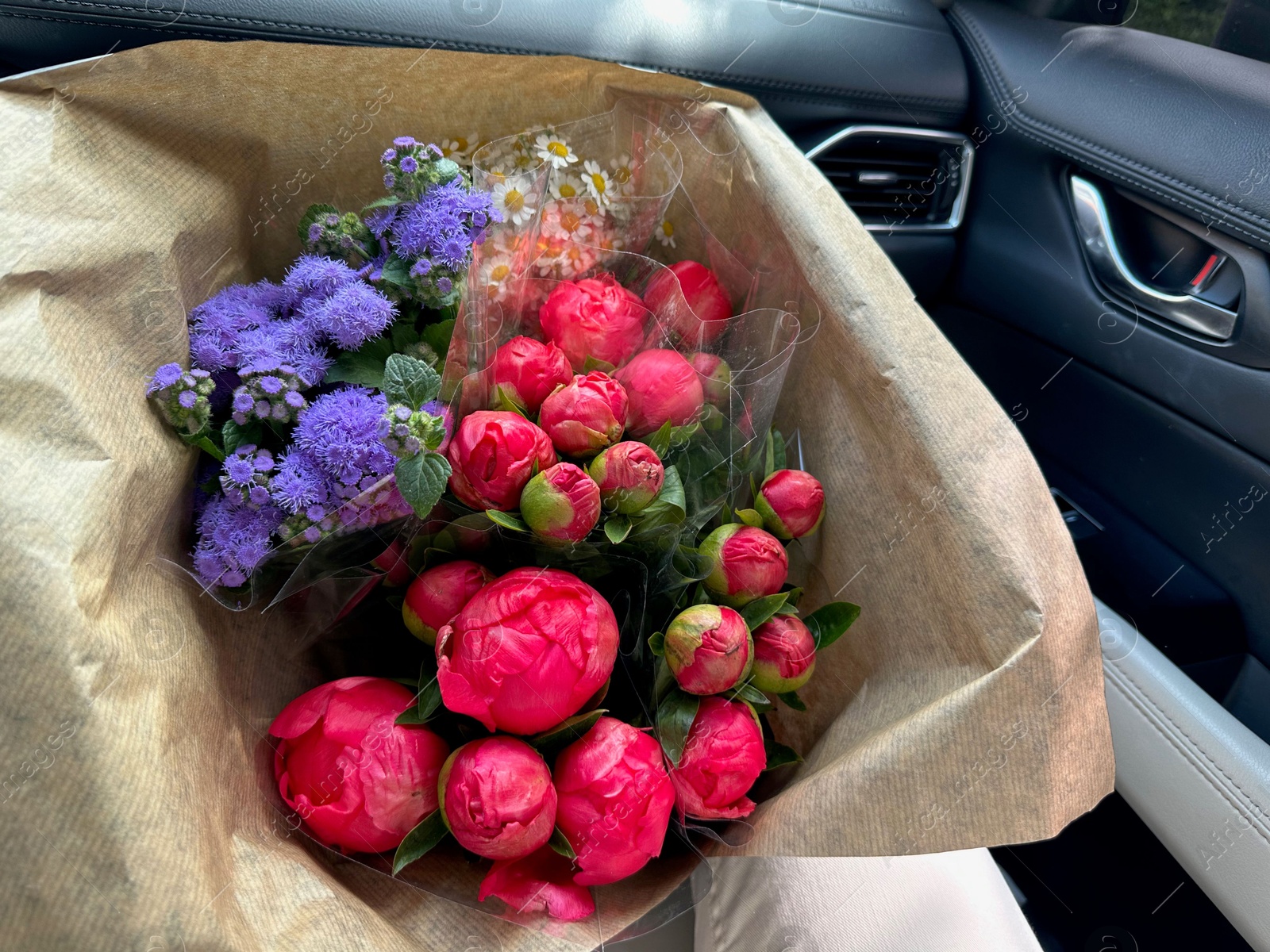 Photo of Bouquets of beautiful flowers in car, closeup