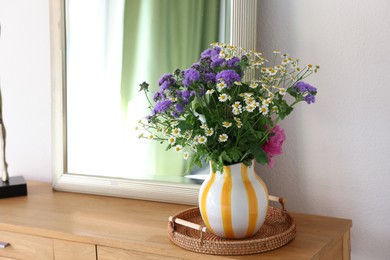 Photo of Vase with beautiful flowers on wooden table indoors, space for text