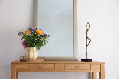 Photo of Beautiful flowers in vase and mirror on wooden table indoors