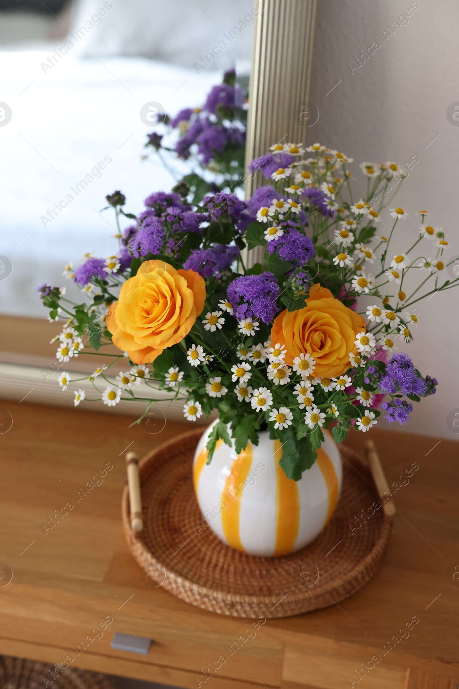 Photo of Beautiful flowers in vase and mirror on wooden table indoors