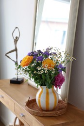 Photo of Beautiful flowers in vase and mirror on wooden table indoors