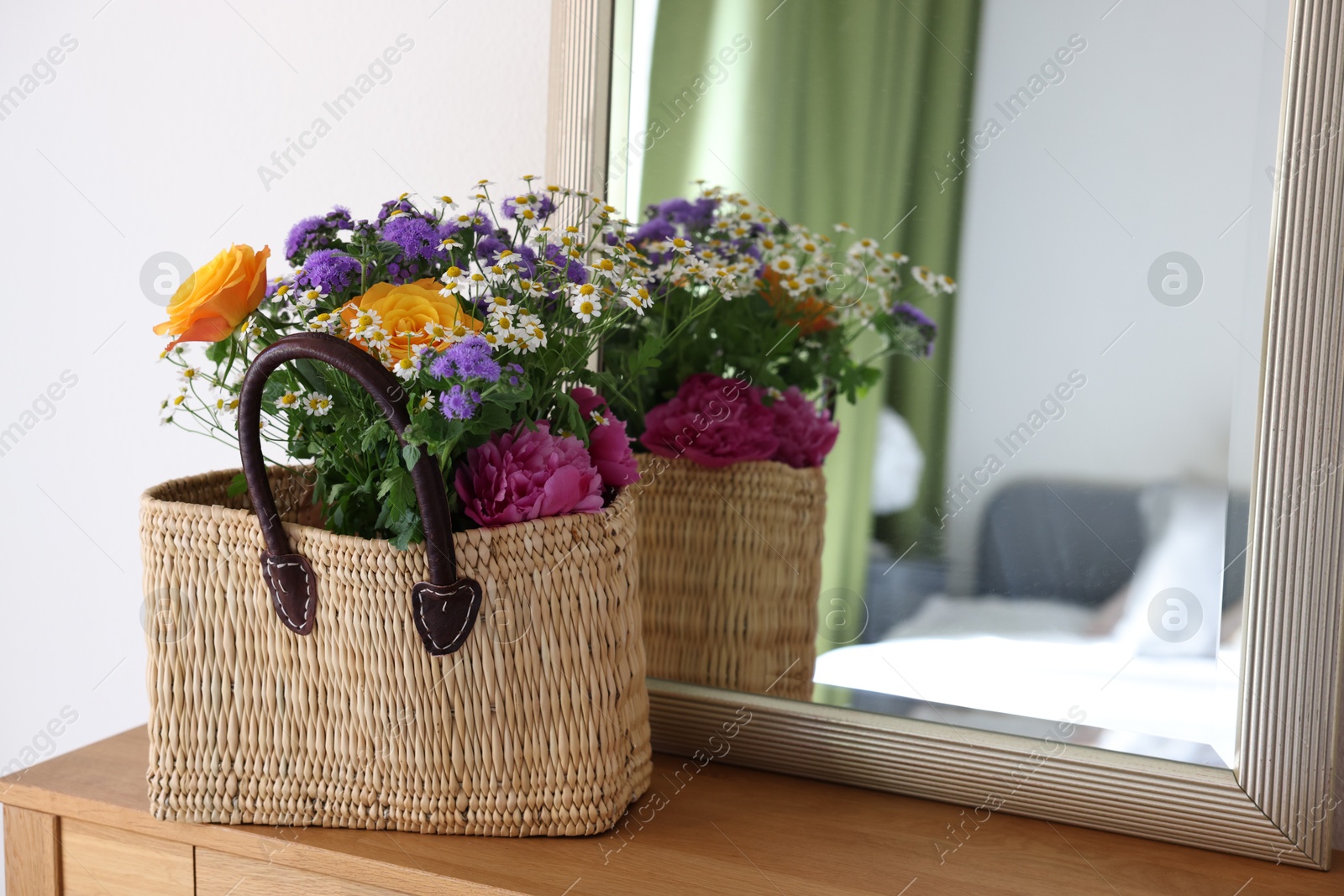 Photo of Wicker basket with beautiful flowers on wooden table indoors