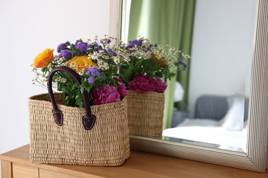 Wicker basket with beautiful flowers on wooden table indoors