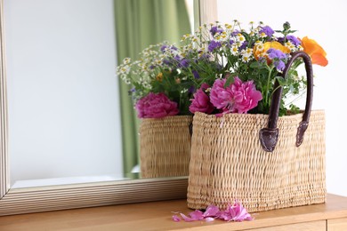 Photo of Wicker basket with beautiful flowers on wooden table indoors, space for text