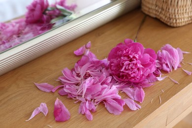 Beautiful pink peony and petals on wooden table indoors, closeup